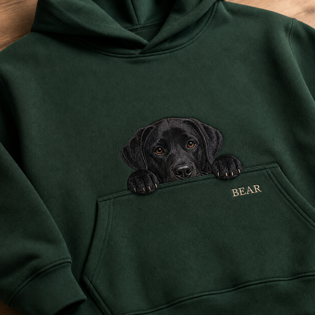 Black Labrador pocket peek embroidery detail on a forest green hoodie