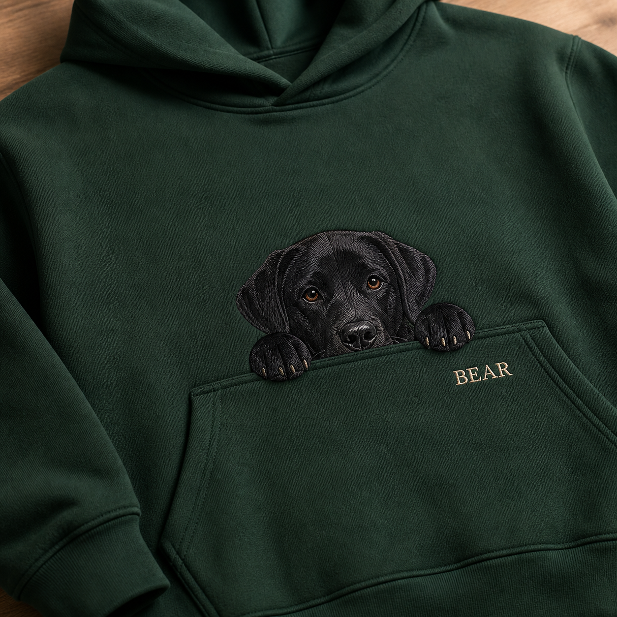 Black Labrador pocket peek embroidery detail on a forest green hoodie